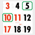 Japanese calendar page with a grid of bold dates; red numbers on 3, 5, 10, 11, and 17; black numbers on other days. Green decorative frames highlight 5, 10, and other dates; small orange text marks events like 成人の日 in the center.